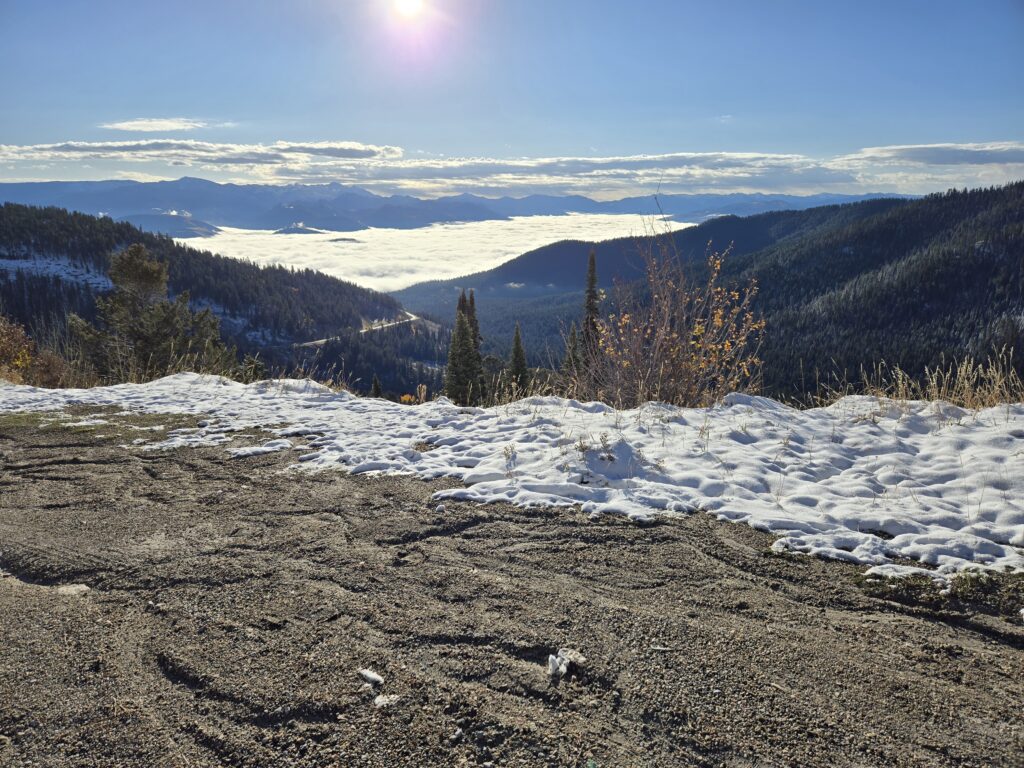 View from mountain with snow in foreground and clouds in valley below